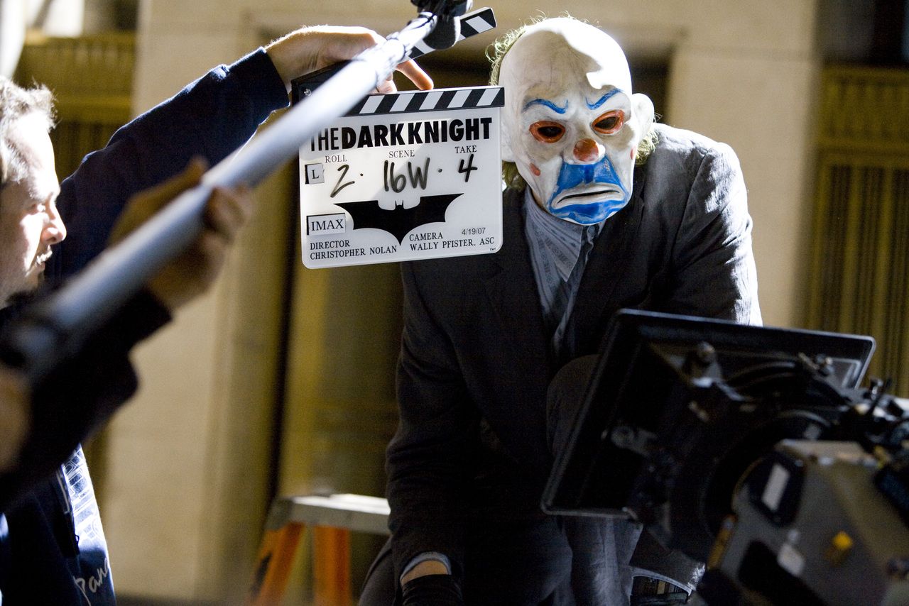 Behind-the-scenes image of the Joker scene setup with a production slate visible.