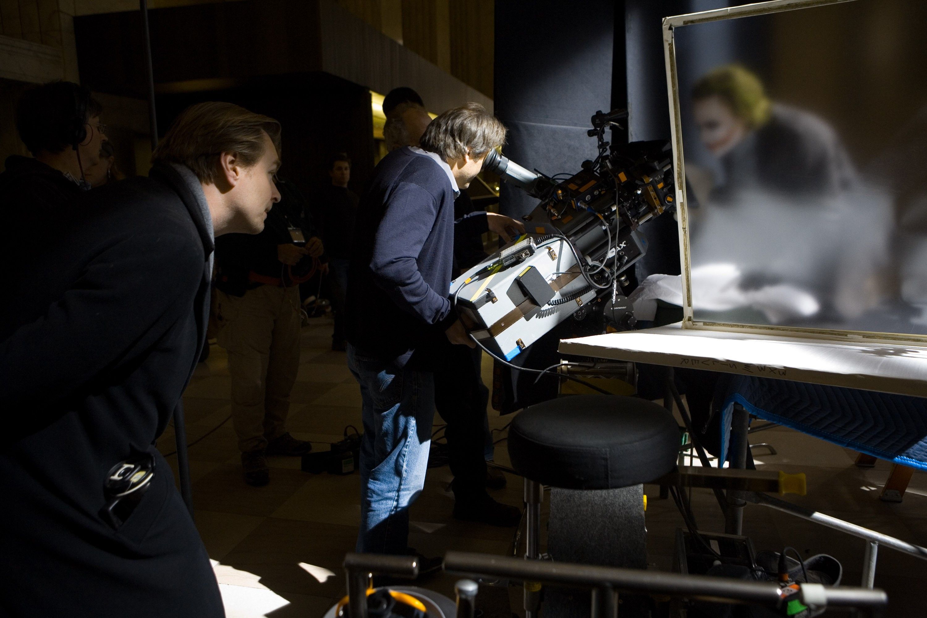 Behind-the-scenes image of camera and lighting equipment around an interior table setup for The Dark Knight.